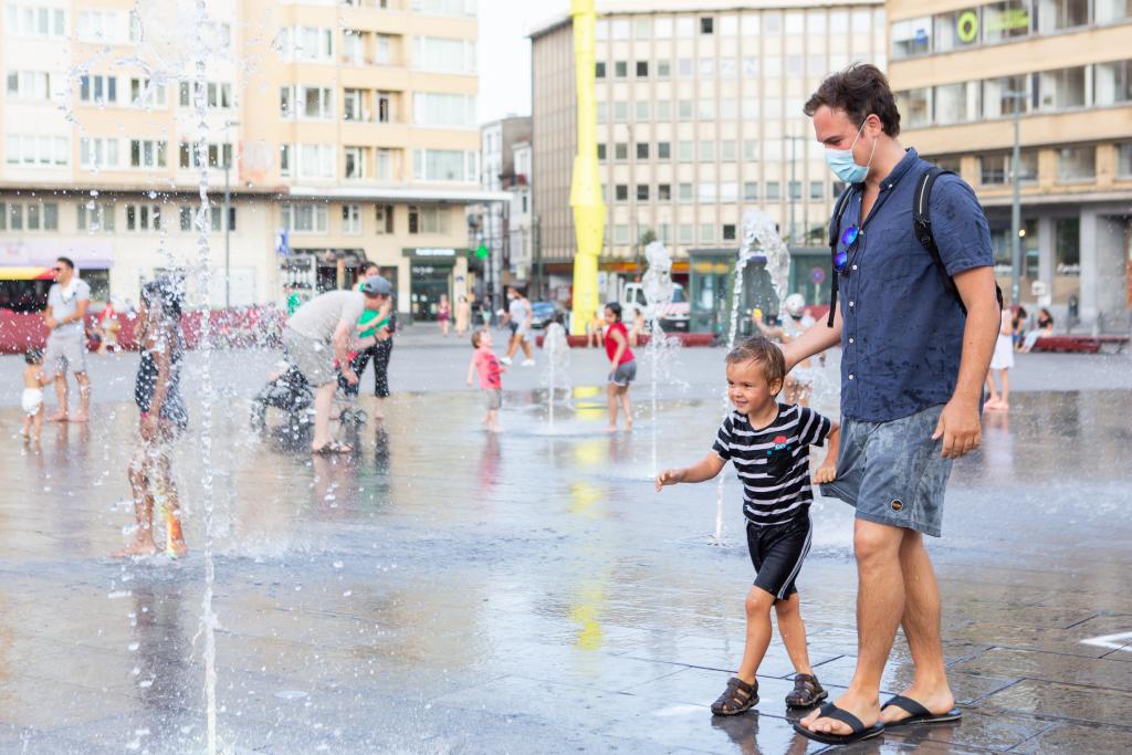 A child playing in the water jets with his father